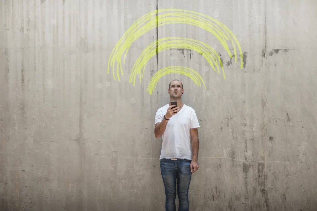 Mann prüft WLAN-Empfang am Smartphone – stabiles WLAN für Gäste und Mitarbeiter